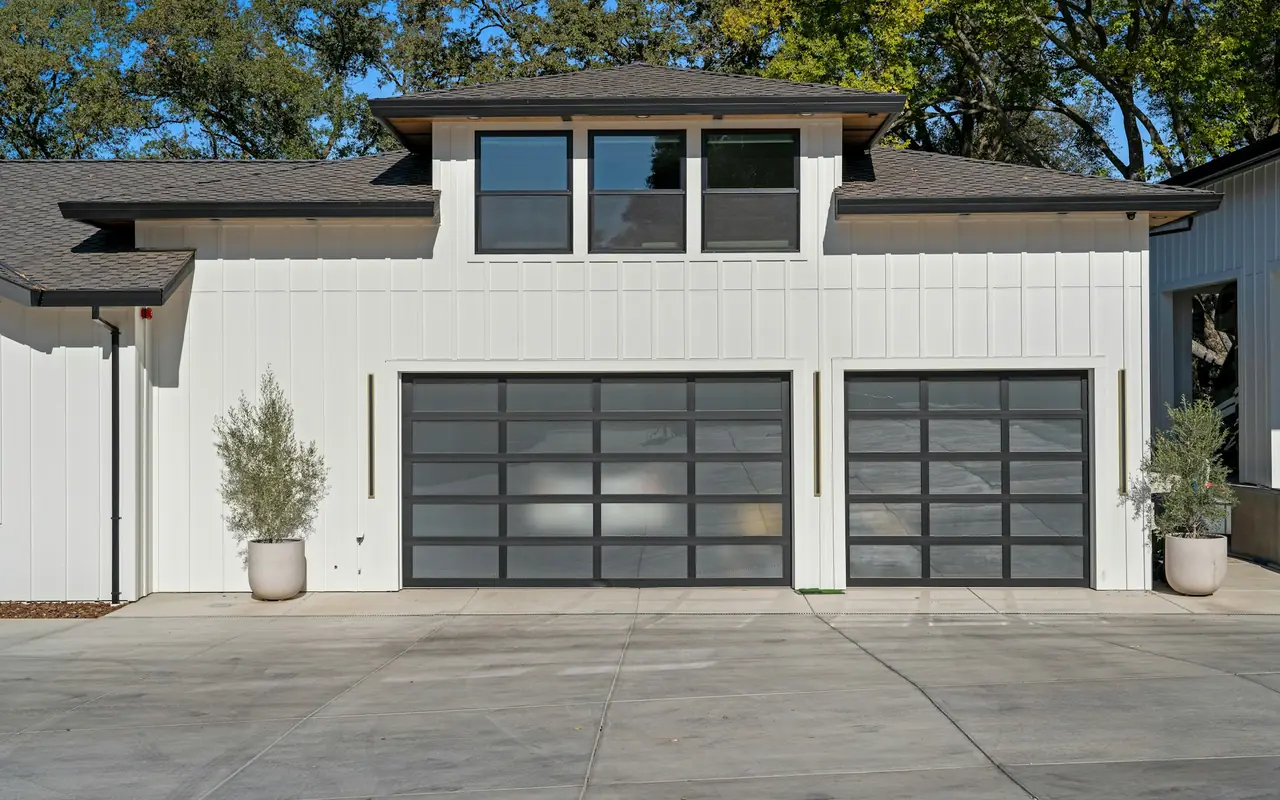 Two-car garage with modern glass-panel sectional doors on a white home