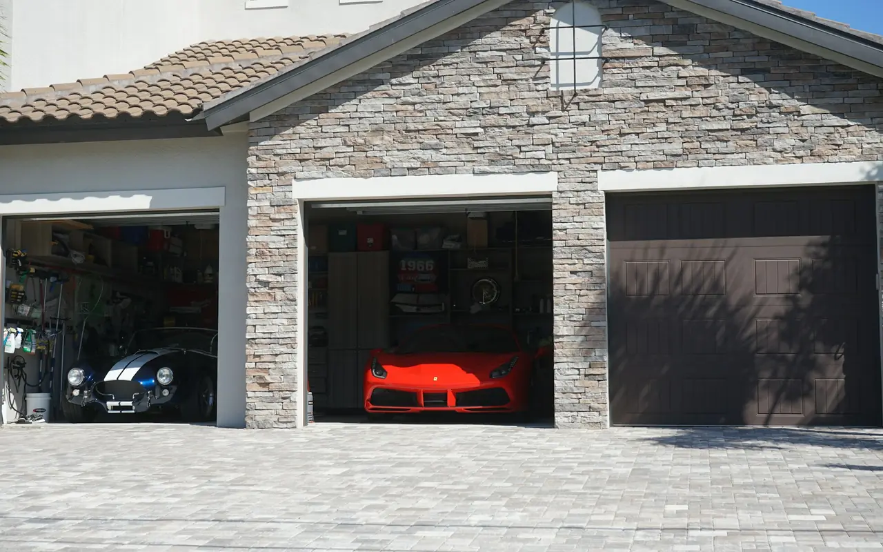Open garage bays on a stone-front home with cars parked inside